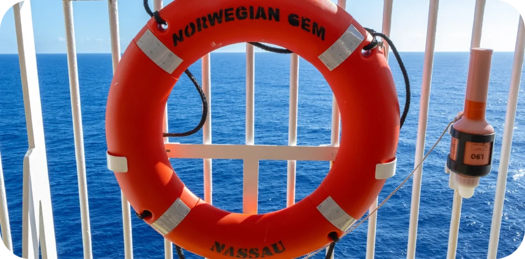 Close-up view of an orange life ring hanging on a white railing on a ships deck - Cruise to the Edge