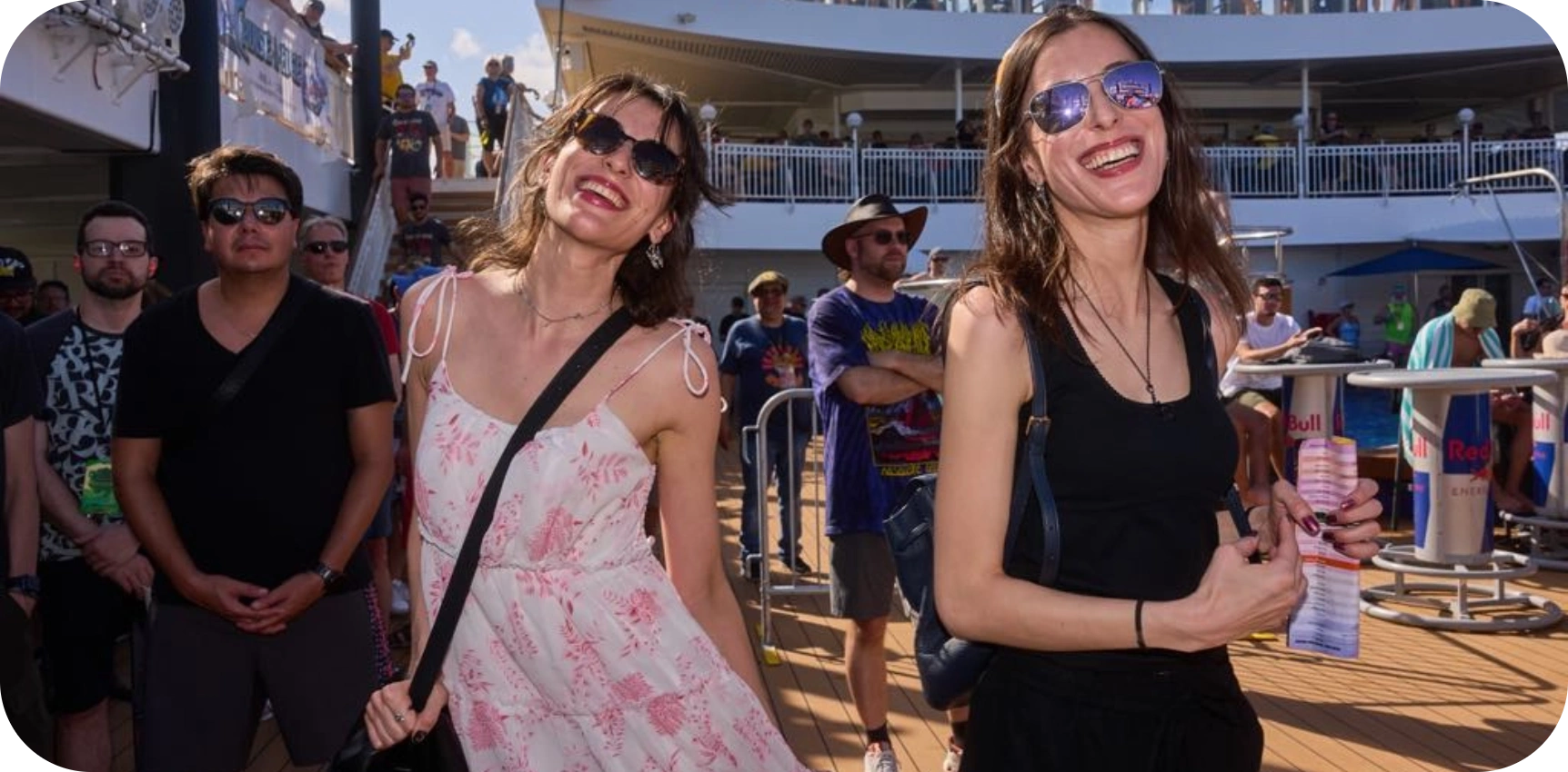 Two women smile joyfully among a crowd of people on what appears to be the deck of a cruise ship - Cruise to the Edge