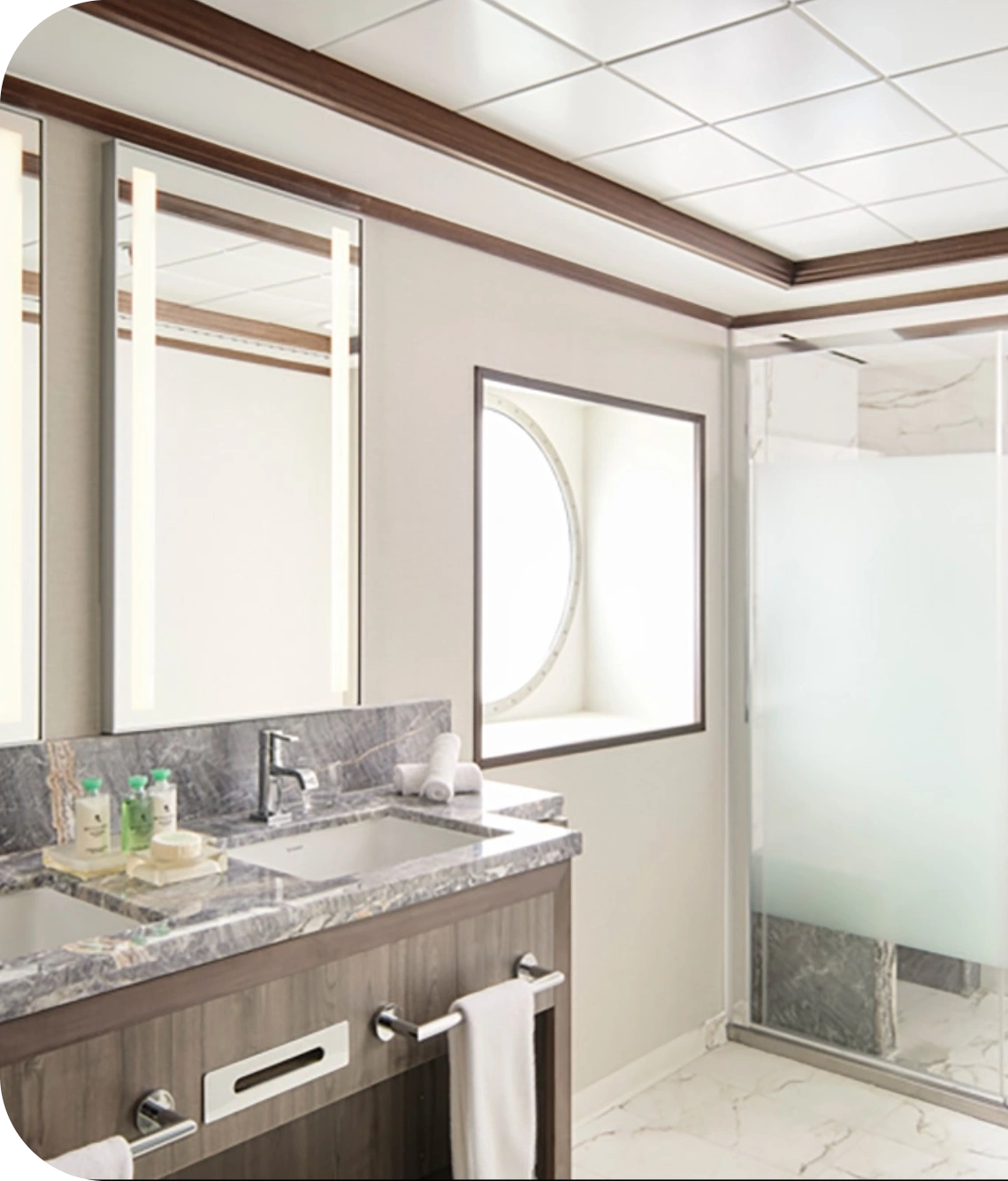 Contemporary bathroom with a double-sink vanity, marble countertop, and glass shower enclosure.